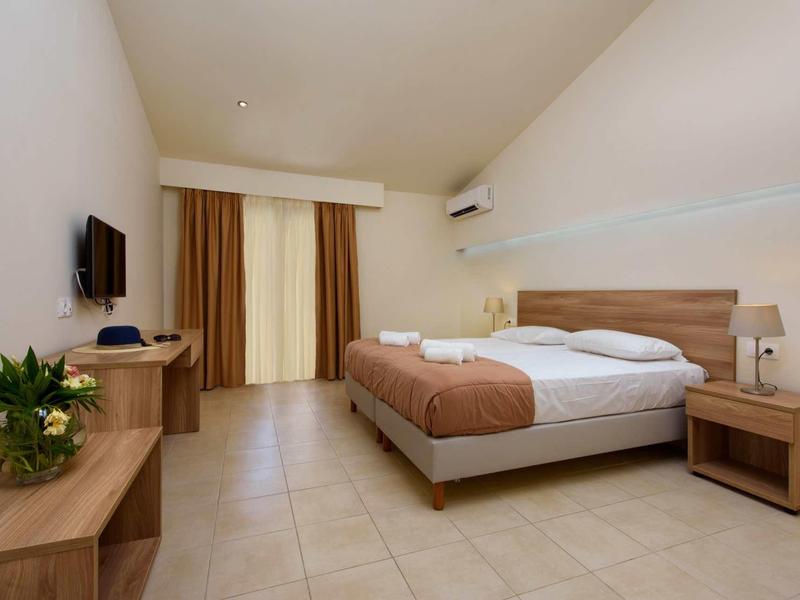 Modernes, schlichtes Schlafzimmer mit großem Bett, Holzmöbeln, Flachbildschirm und natürlicher Beleuchtung.