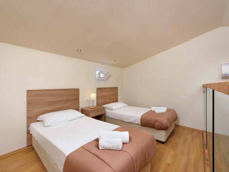 Zweibettzimmer mit zwei Einzelbetten, Holzboden, Nachttisch und weißem Wandschrank.