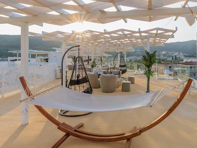 Moderne Dachterrasse mit Hängematte, Schaukelstühlen und Blick auf Berge bei Sonnenuntergang.