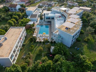 Modern hotel complex with a pool, surrounded by greenery and multiple buildings.