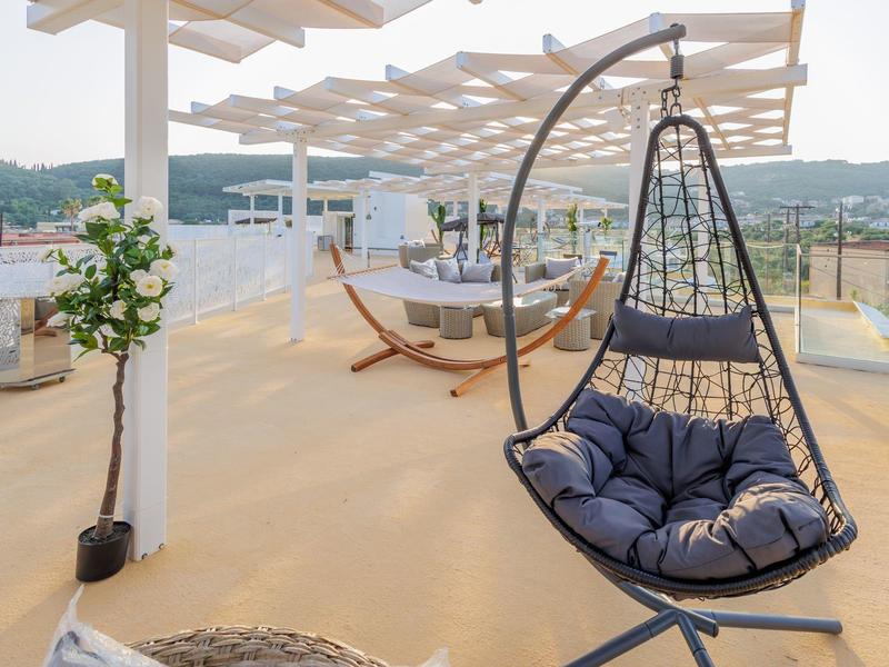 Spacious outdoor terrace with hanging chair, hammock, and scenic mountain views under pergola.