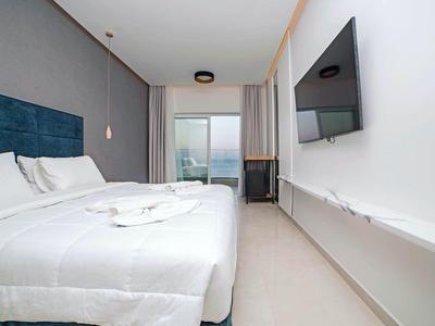 Moderne hotelkamer met groot bed, flatscreen-tv en balkon met zeezicht.