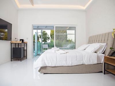 Frau in Badeanzug am Hotelpool mit Flugzeug im Hintergrund über dem Meer.