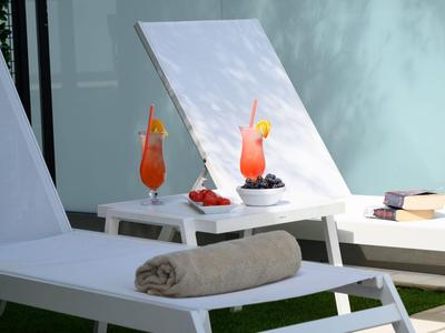 Zwei Liegestühle mit Tabletts, Obst und erfrischenden Getränken im Freien.