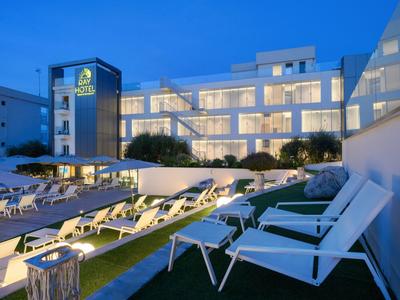 Moderner Hotelkomplex mit beleuchteten Zimmern und Liegestühlen am Abend