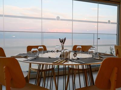 Essbereich im Hotel mit Blick auf ruhiges Meer durch große Fenster