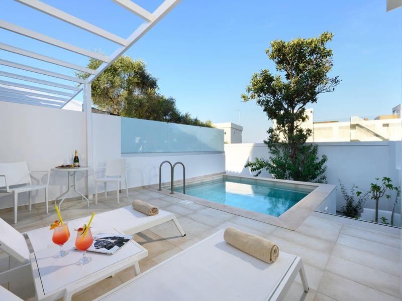 Moderne buitenzwembad met ligstoelen en overdekte zithoek onder een heldere hemel.