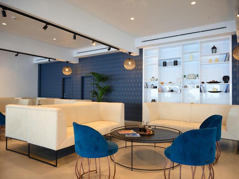 Moderne hotelkamer met blauwe muren, witte banken en blauwe stoelen