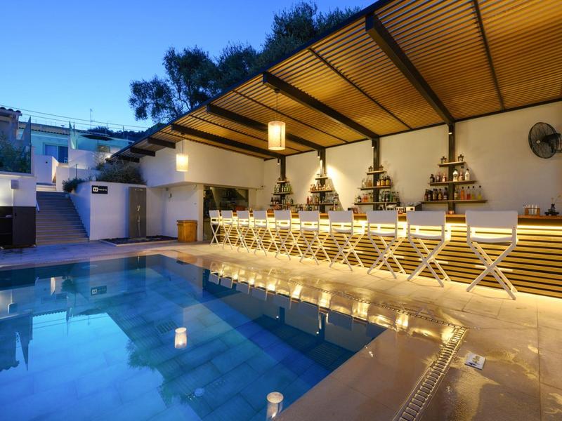Verlichte zwembadbar met moderne krukken en dak bij schemering.