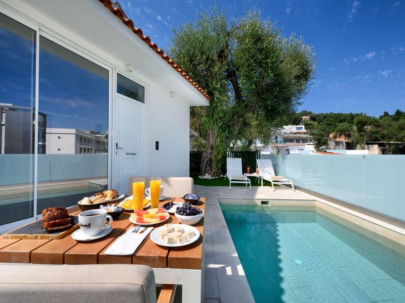 Moderne terras met eettafel en zwembad onder een heldere hemel bij een hotel.