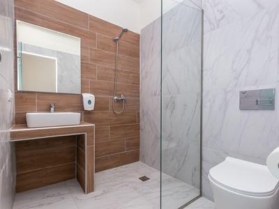 Moderní koupelna s dřevěnou stěnou, skleněnou sprchou, umyvadlem a toaletou.