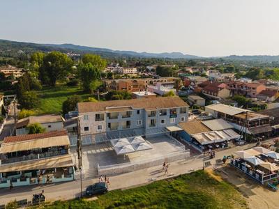 Pohled na hotel s bazénem a okolními budovami v zelené krajině.