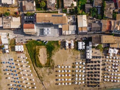 Letecký pohled na pláž s deštníky, přilehlými budovami a čistou vodou.