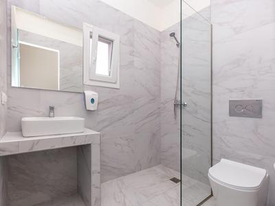 Moderní koupelna se sprchou, umyvadlem, toaletou a velkým zrcadlem.