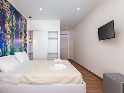 Moderní hotelový pokoj s manželskou postelí, barevným nástěnným uměním a televizí s plochou obrazovkou.