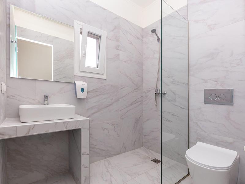 Moderní koupelna se sprchou, umyvadlem, toaletou a velkým zrcadlem.