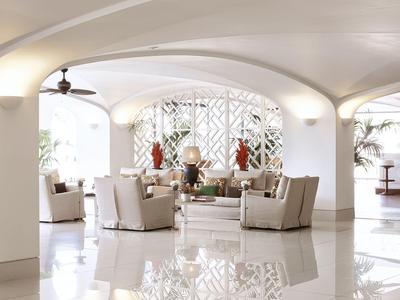 Lichte, elegante hotellobby met witte meubels en decoratieve planten.