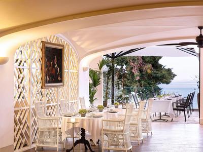 Elegante eetkamer met wit gedekte tafel en uitzicht op zee en terras.