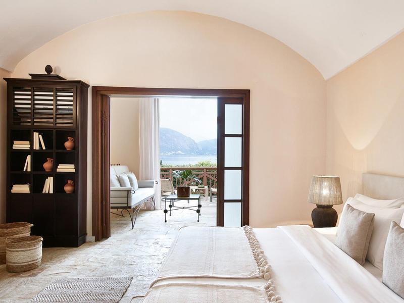 Chambre d'hôtel lumineuse avec lit, lampe et vue sur terrasse avec panorama montagne.