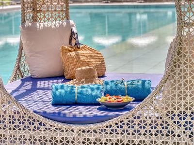 Entspannende Poolnische mit blauem Kissen, Handtüchern und Obstteller für Urlaubsgäste.