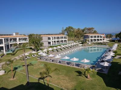 Großer Hotelpool mit weißen Liegestühlen und Sonnenschirmen, umgeben von mehrstöckigen Gebäuden.