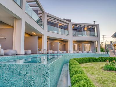 Moderner Hotelkomplex mit Pool, Terrasse und Rasenfläche bei klarem Himmel.