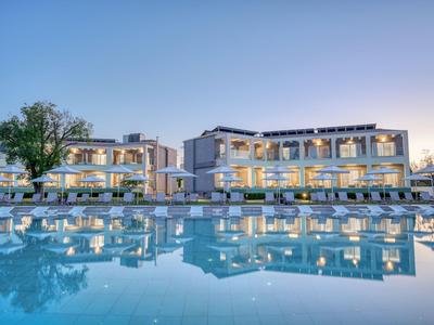 Moderner Hotelkomplex mit beleuchtetem Pool am Abend und klarem Himmel.