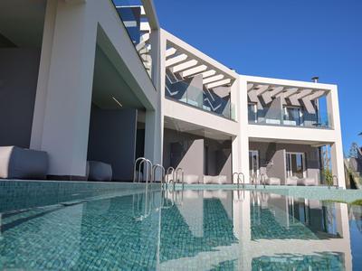 Moderne Villa mit großem Pool vor klar blauem Himmel, ideal für luxuriösen Urlaub.