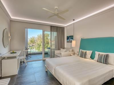 Modern eingerichtetes Hotelzimmer mit Doppelbett, Schreibtisch, TV und Balkon mit Meerblick.