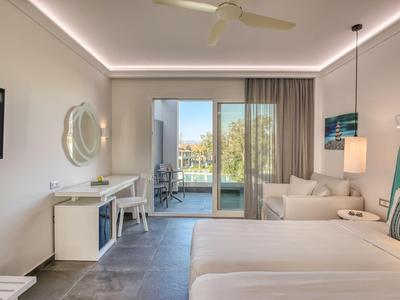 Moderner Hotelraum mit Doppelbett, Schreibtisch und Balkon mit Blick auf Wasser.