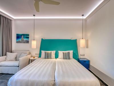 Helles Hotelzimmer mit zwei Einzelbetten, türkisfarbenem Kopfteil und modernem Interieur.