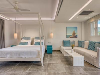 Modernes Hotelzimmer mit weißem Himmelbett, Sofa und dekorativen Kissen.