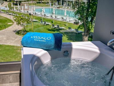 Whirlpool auf einem Balkon mit Blick auf einen Pool und Gartenbereich eines Hotels.