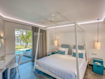 Modernes Hotelzimmer mit Himmelbett, Schreibtisch und Blick auf den Pool im Freien.