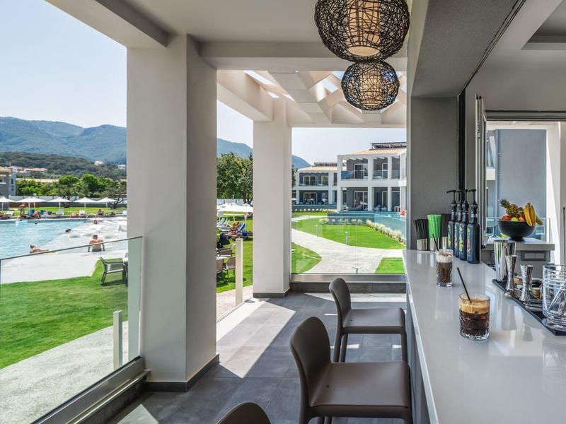 Moderní venkovní bar s výhledem na bazén a horskou krajinu v hotelovém resortu.