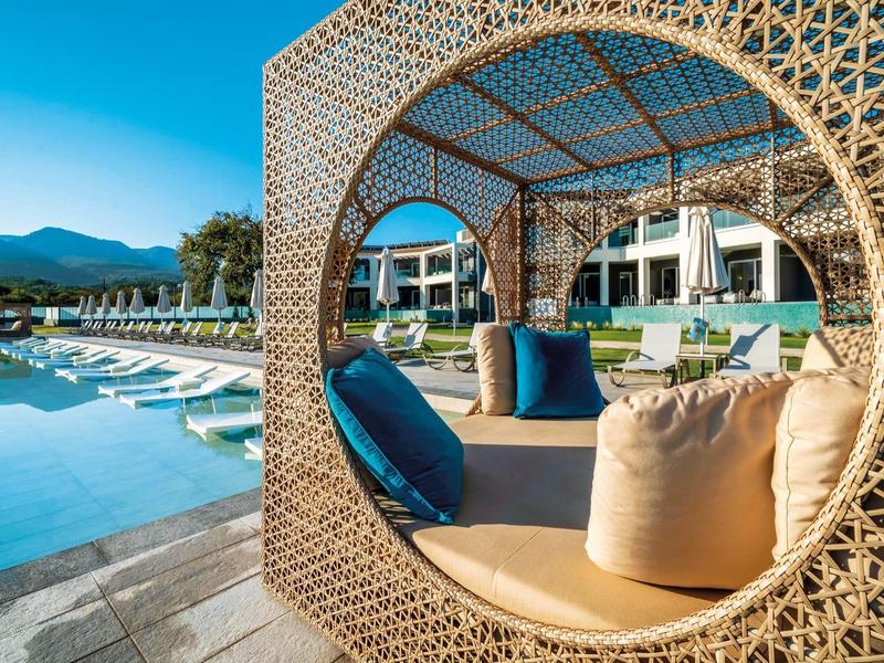 Lounge křesla u bazénu resortu s výhledem na hory.