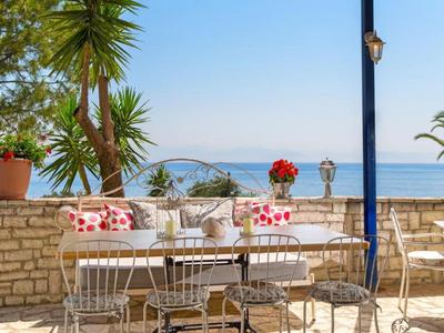 Terraza con sillas y mesas blancas, vista al mar y cielo azul.