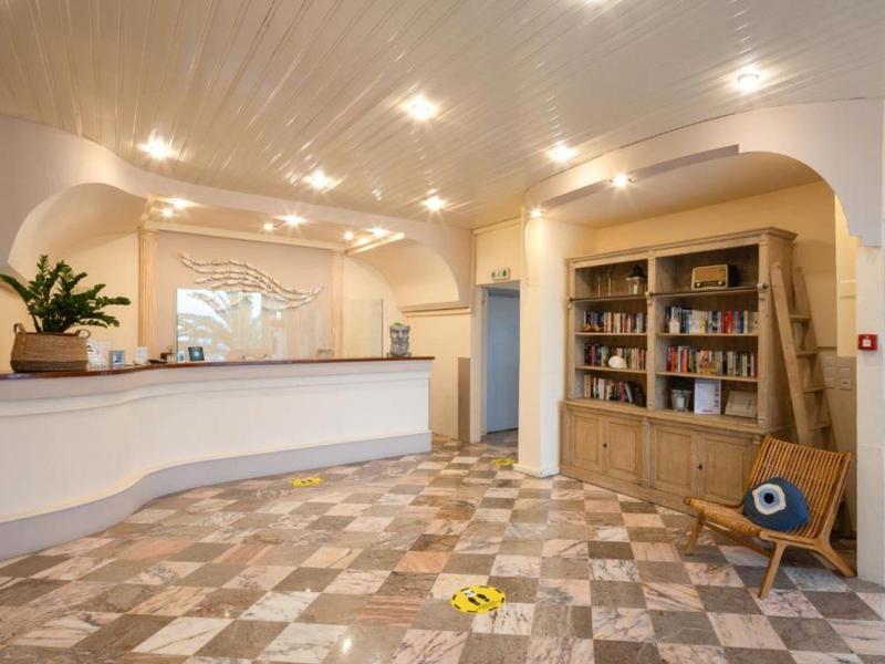 Jasna lobby hotelowa z recepcją, półką na książki i krzesłem na marmurowej podłodze.