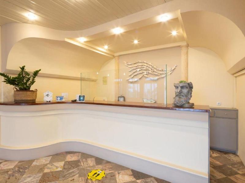 Jasna recepcja hotelowa z zakrzywionym białym biurkiem i dekoracjami na blacie.