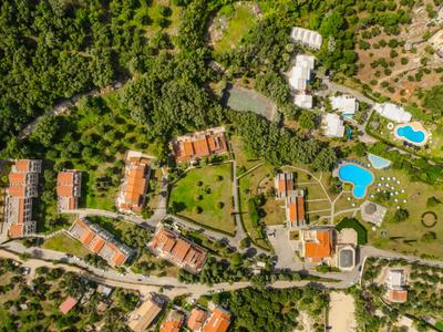 Vista aerea di un hotel con più edifici, piscine e molta vegetazione.