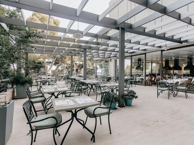 Espace extérieur moderne et aéré d'un hôtel avec tables, chaises et lumière naturelle abondante.