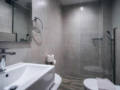 Bagno moderno con lavabo, WC e doccia a pavimento in tonalità neutre.