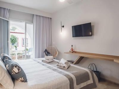 Camera luminosa arredata con letto, TV a parete e accesso al balcone.