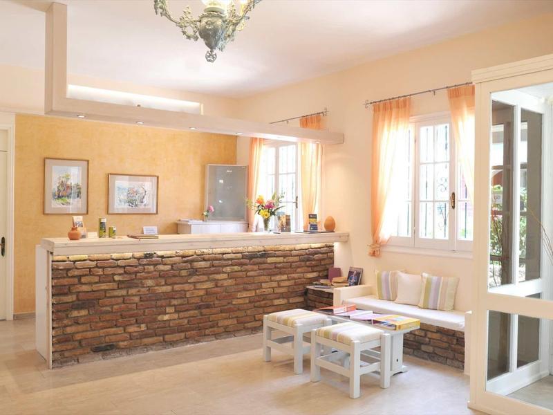 Světlá hotelová hala s rustikálním recepčním pultem a posezením u velkých oken.