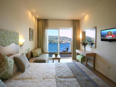 Hotelkamer met twee eenpersoonsbedden, balkon met uitzicht op zee, beige inrichting en moderne verlichting.