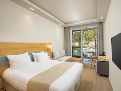 Habitación de hotel moderna con cama doble, balcón y televisor en la pared