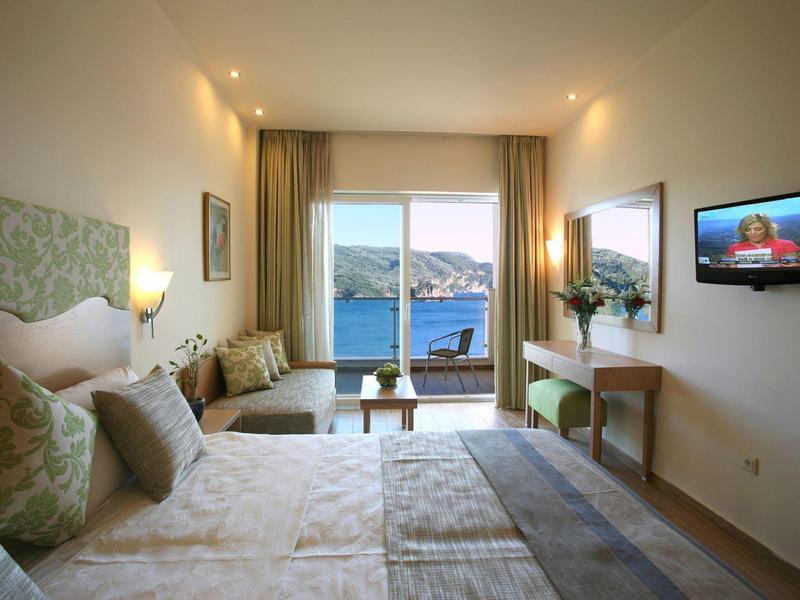 Hotelkamer met twee eenpersoonsbedden, balkon met uitzicht op zee, beige inrichting en moderne verlichting.