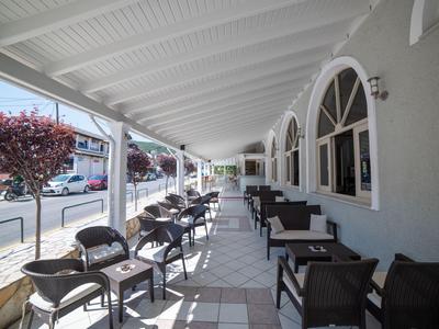 Covered outdoor café terrace with tables and chairs along a street.