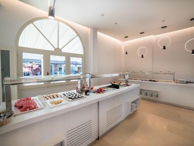 Moderní bufet s různými pokrmy v světlé, čisté místnosti s velkými okny.