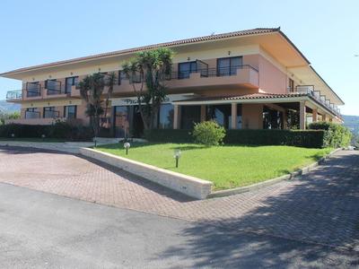 Modern tweeverdiepingen hotel met grote balkons en goed onderhouden gazon onder een heldere lucht.